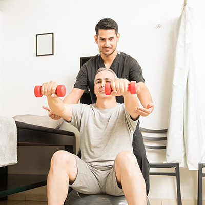Physical therapist assisting a resident using small red hand weights.
